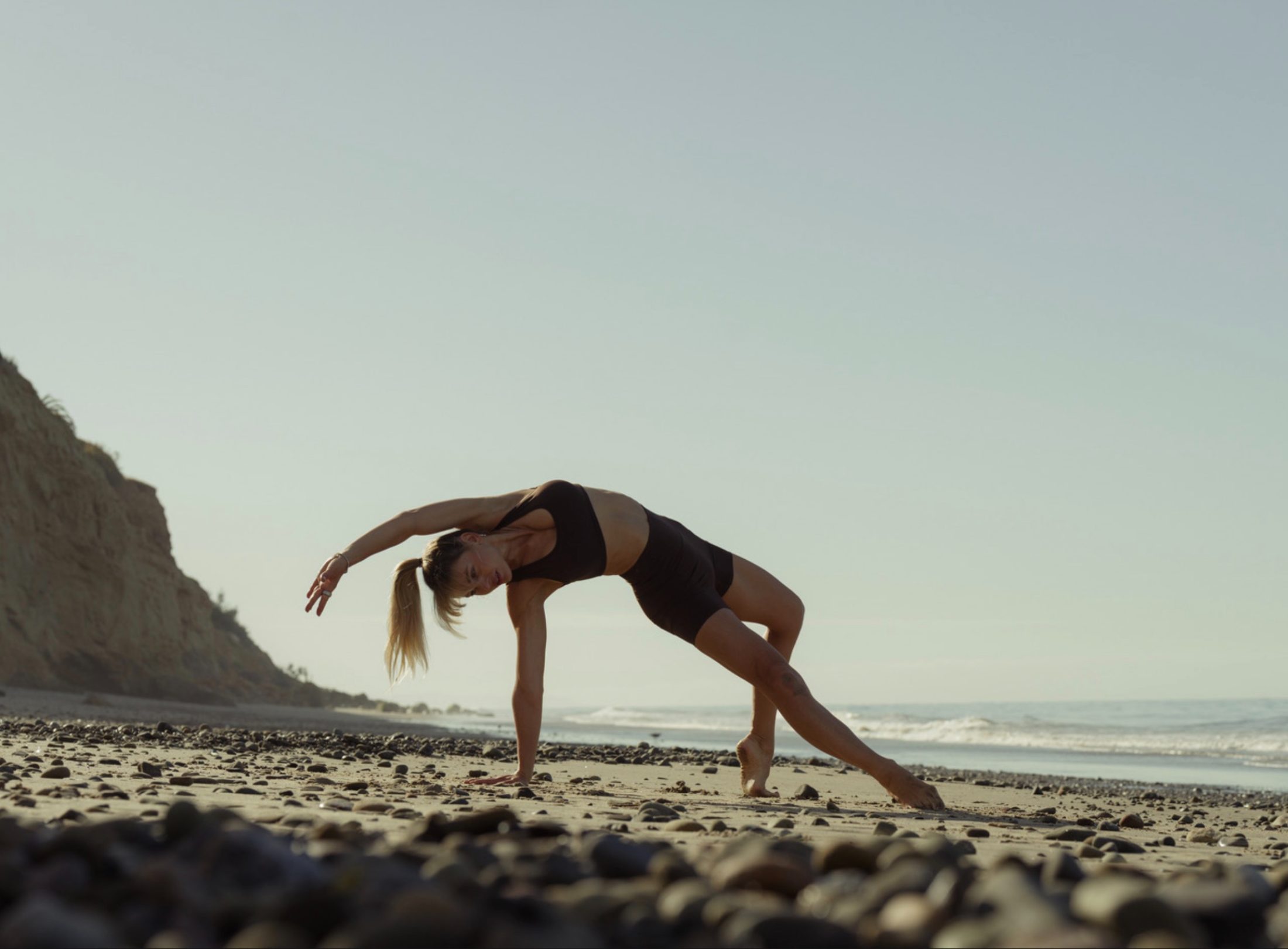 Figure in bridge pose on the beach at golden hour